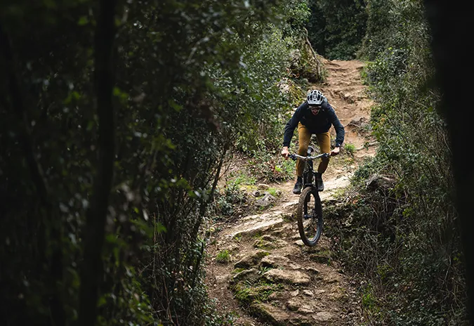 Rider descending a rocky forest trail