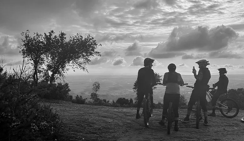 Black and white photo of riders on a hilltop at sunset